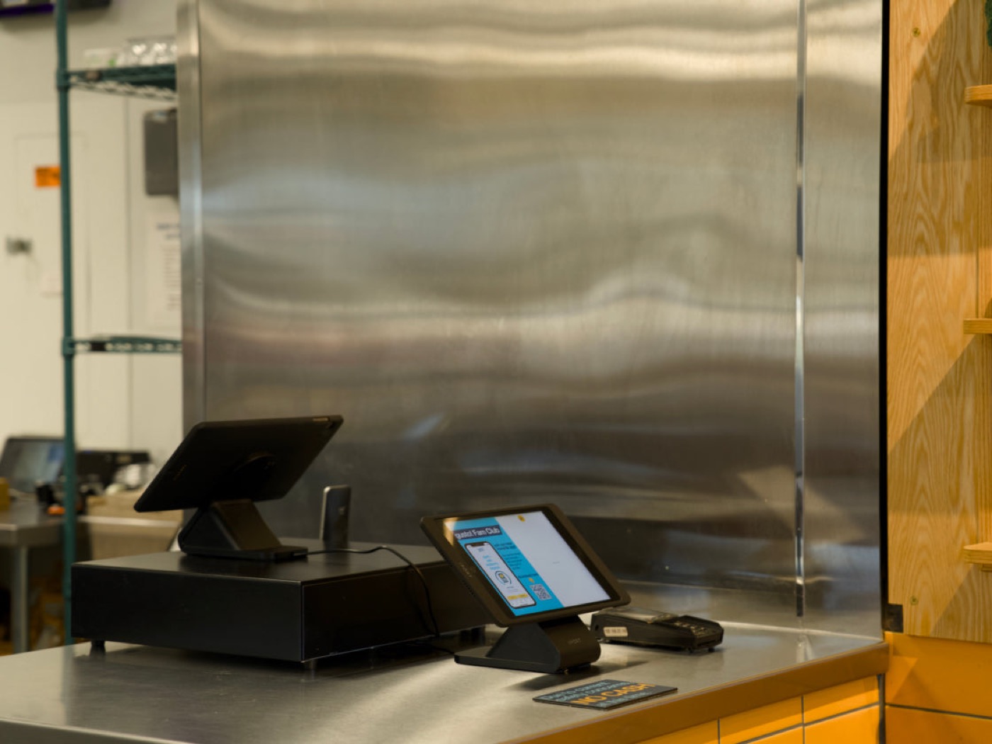 An iPad angled on an IPORT stand at a service counter beside the POS and card reader